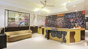 A modern reception area with a counter, a ceiling fan, and a sofa. - Hotel Hilife (New Delhi)