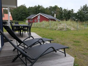 Eine Terrasse mit Liegestühlen, einem Tisch und Stühlen.