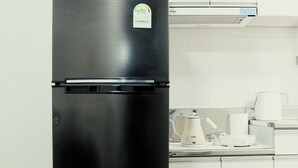 Ein schwarzer Kühlschrank in einer Küche mit weißen Schränken und einer Mikrowelle darüber.