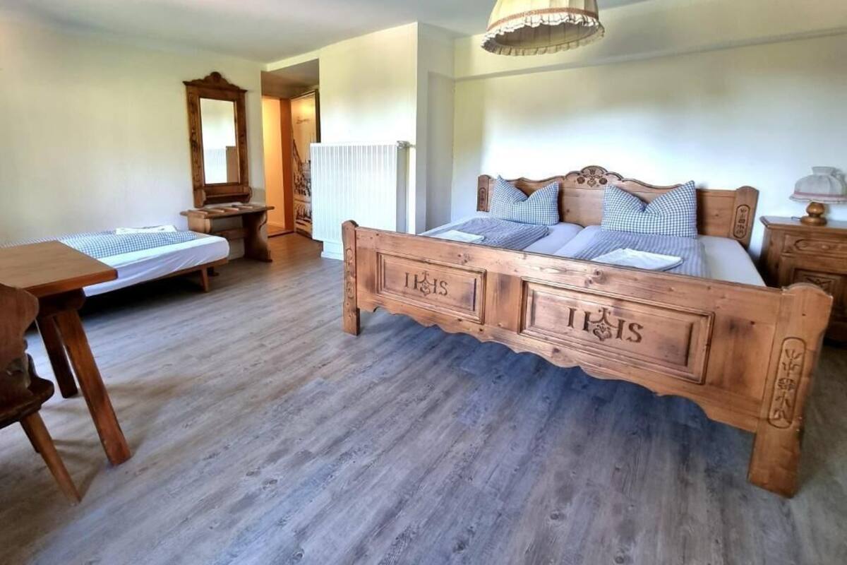 Ein Schlafzimmer mit einem hölzernen Bett, einem Schreibtisch aus Holz und einem Spiegel.