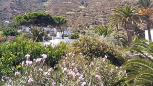 A mountain with a clear sky, surrounded by greenery and buildings. - Ada Stromboli House in Piscità, close to the beach and the Cave of Aeolus. (Stromboli)