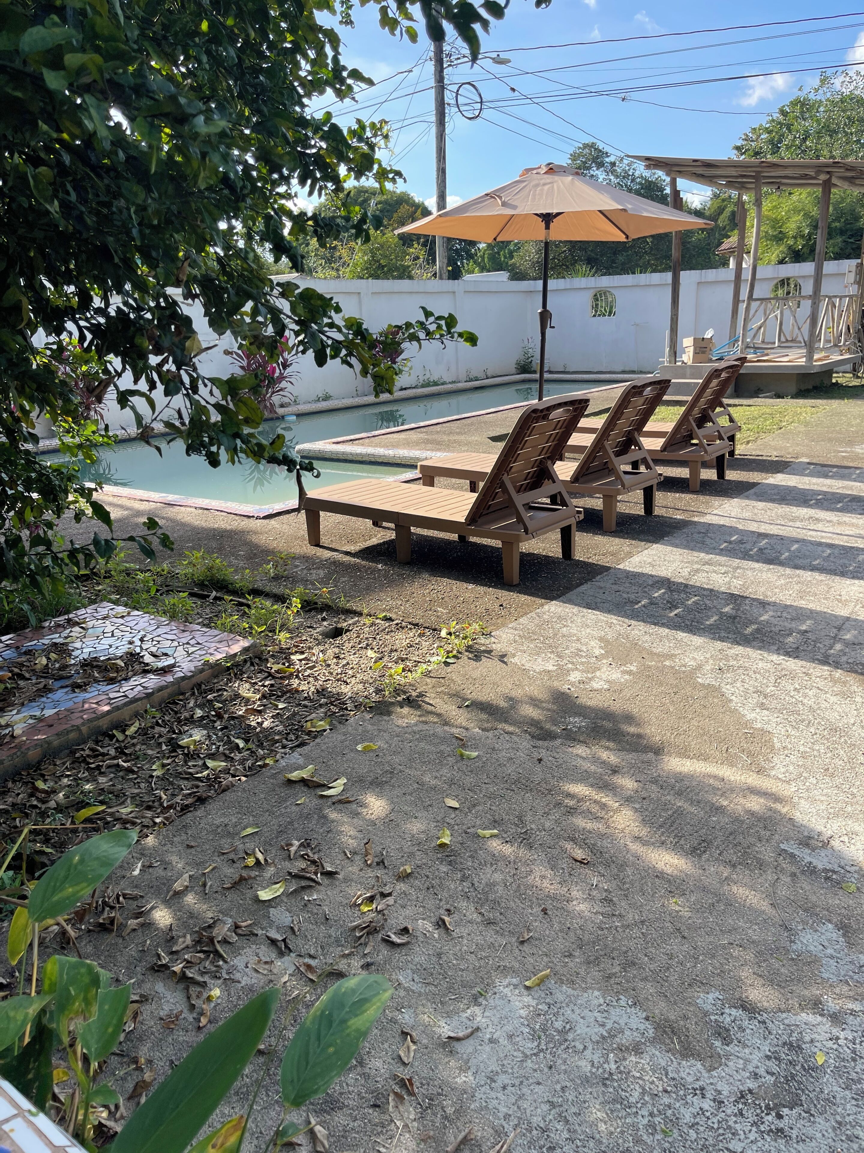 A pool area with lounge chairs and a pergola.