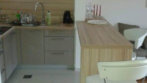 A compact kitchen with a sink, cabinets, a coffee maker, and a small dining area with chairs. - Villa Ivan Vodice (Vodice)