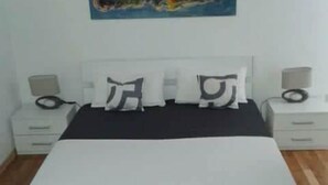 A bedroom with a bed, two bedside tables, and a nightstand with a lamp. - Villa Ivan Vodice (Vodice)