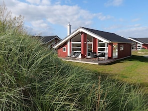 A modern house with a red exterior, a covered patio, and a chimney. - 4 Star Holiday Home in Grossenbrode (Grossenbrode)