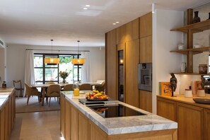A modern kitchen with wooden cabinets, a marble countertop, and a central island with fruit. - Provence Villa luxury, swimming pool, park 2ha, PDJ and Villa Manager included, 10 ' Aix (Aix-en-Provence)