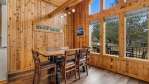 Un intérieur en bois avec une table et des chaises, de grandes fenêtres et une vue sur l’extérieur.