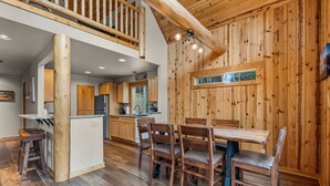 Un intérieur en bois comprenant un coin repas, une cuisine et un espace en mezzanine.