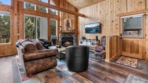 Un intérieur en bois avec une cheminée, un coin salon et de grandes fenêtres.