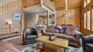 Un intérieur en bois avec un escalier, des meubles en cuir et un coin cuisine.