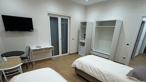 Een hotelkamer met twee bedden, een bureau, een stoel, een televisie en een kledingkast.