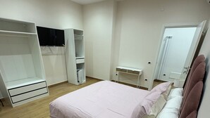 Een slaapkamer met een bed, een kledingkast, een nachtkastje en een spiegel.