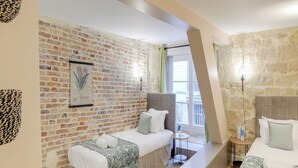 Une chambre d’hôtel avec un mur en briques, un lit avec une tête de lit, une petite table et une fenêtre donnant sur un paysage agréable.