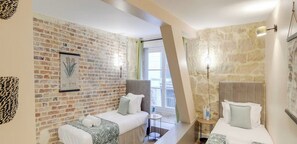 Ein Hotelzimmer mit Backsteinwand, einem Bett mit Kopfteil, einem kleinen Tisch und einem Fenster mit Blick.