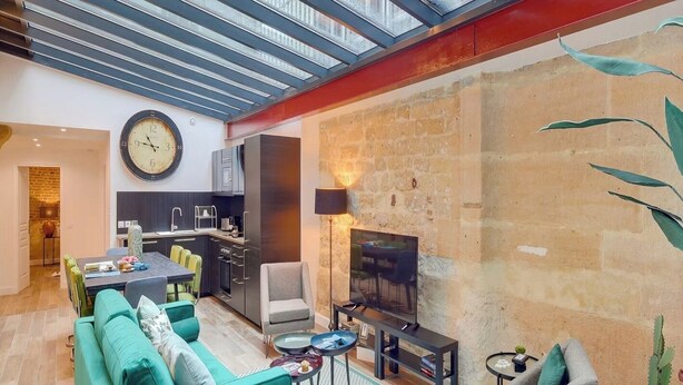 Un salon moderne avec un mur en pierre, un coin repas et une cuisine.