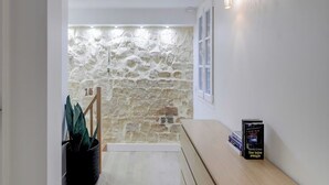 Un couloir avec un mur en pierre, un banc en bois et une plante en pot.