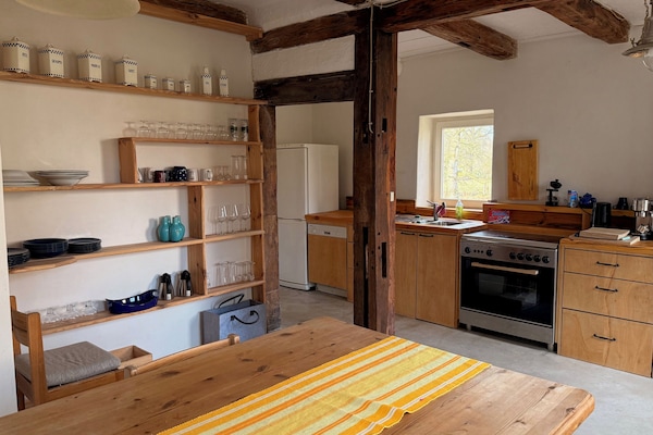 kitchen with a large table, a 5 filed gas stove and coffee/tea accessories.