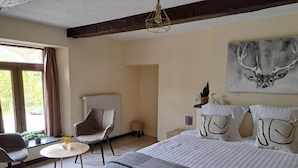 A bedroom with a bed, a chair, a small table, a radiator, and a window with curtains. - Au Coeur D'alle by Belvilla-double Room (Vresse-sur-Semois)