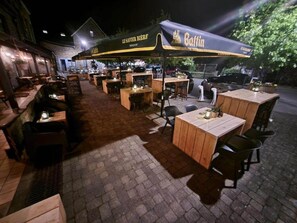An outdoor restaurant with wooden tables and chairs, a covered area with a sign reading 'Bastian,' and a brick-paved patio. - Au Coeur D'alle by Belvilla-double Room (Vresse-sur-Semois)