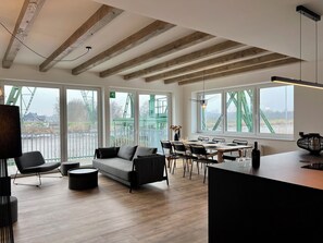 Un interior moderno con techo de madera, ventanas amplias, un sofá, una mesa de comedor y sillas.