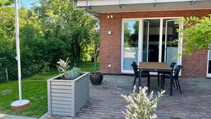 A patio with a table and chairs, a planter box, and a sliding glass door. - Apartment house „Osten – An der Schwebefähre“ – Apartment 4 (Osten)