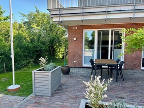 Un patio con mesa y sillas, una jardinera y un ventanal corredera.