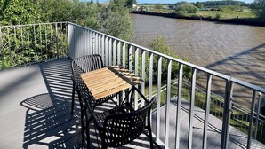 Un balcone con tavolo e sedie, affacciato su un fiume.