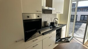 A modern kitchen with a built-in oven, a kettle, and a dishwasher. - Stylish 2BR With 1LR Near to City Center (Ghent)