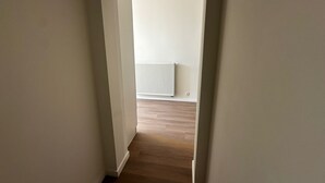 A narrow hallway with wooden flooring leading to a room with a white radiator. - Stylish 2BR With 1LR Near to City Center (Ghent)