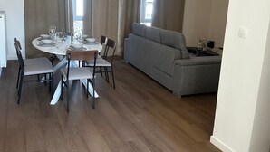 A modern living room with a dining area, grey sofa, and wooden flooring. - Stylish 2BR With 1LR Near to City Center (Ghent)