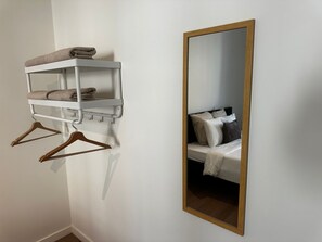 A bathroom with a white towel rack, a mirror with a wooden frame, and a bed with pillows. - Stylish 2BR With 1LR Near to City Center (Ghent)