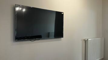 A wall-mounted flat-screen TV, a white radiator, and a plain wall.