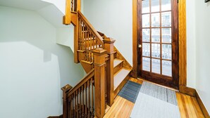 A wooden staircase with a handrail, a door with glass panels, and a patterned rug on the floor. - Spacious & Cozy 4BR Boston Apt with view / Family Gathering - 90/2 (Boston)