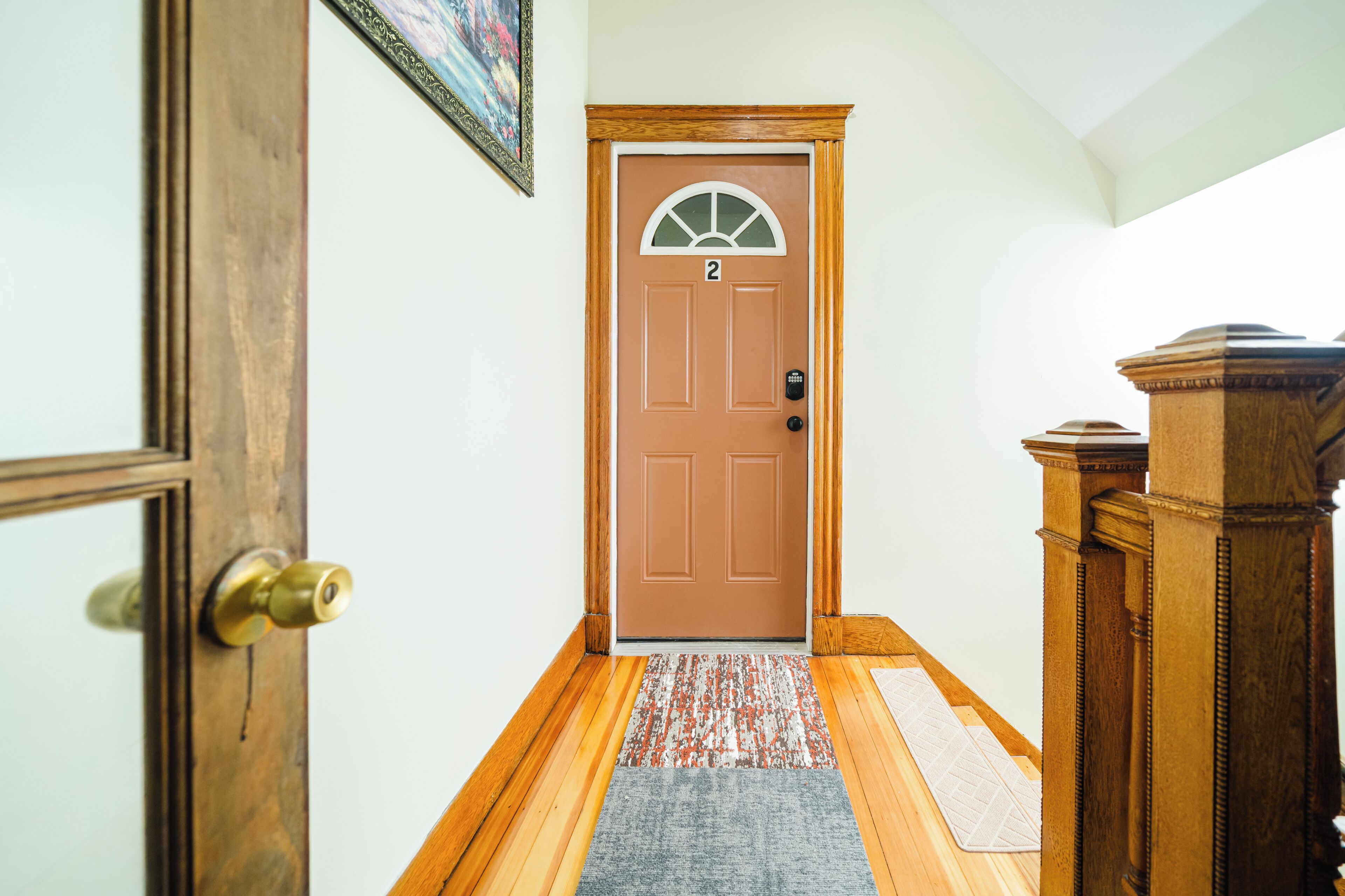 A wooden door with a number '2' above it, a small window, and a wooden floor with a rug.