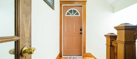 A wooden door with a number '2' above it, a small window, and a wooden floor with a rug.