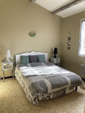 A bedroom with a bed, a nightstand, a lamp, a wall decoration, and a window. - "L'Olivier"—air-conditioned house / 700 m² (Ruoms)