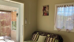 A room with a sofa, a window with sheer curtains, an air conditioning unit, and a ceiling fan. - "L'Olivier" air-conditioned house / 700 m2 (Ruoms)