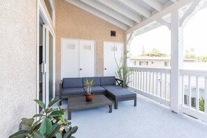 A balcony with a sofa, a coffee table, and potted plants. - Ocean Beach Compound, Walk to Beach, Sleeps 19, Driveway and 3 parking garages (San Diego)