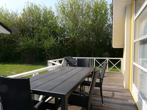 A deck with a table and chairs, surrounded by greenery. - 4 Star Holiday Home in Grossenbrode (Grossenbrode)