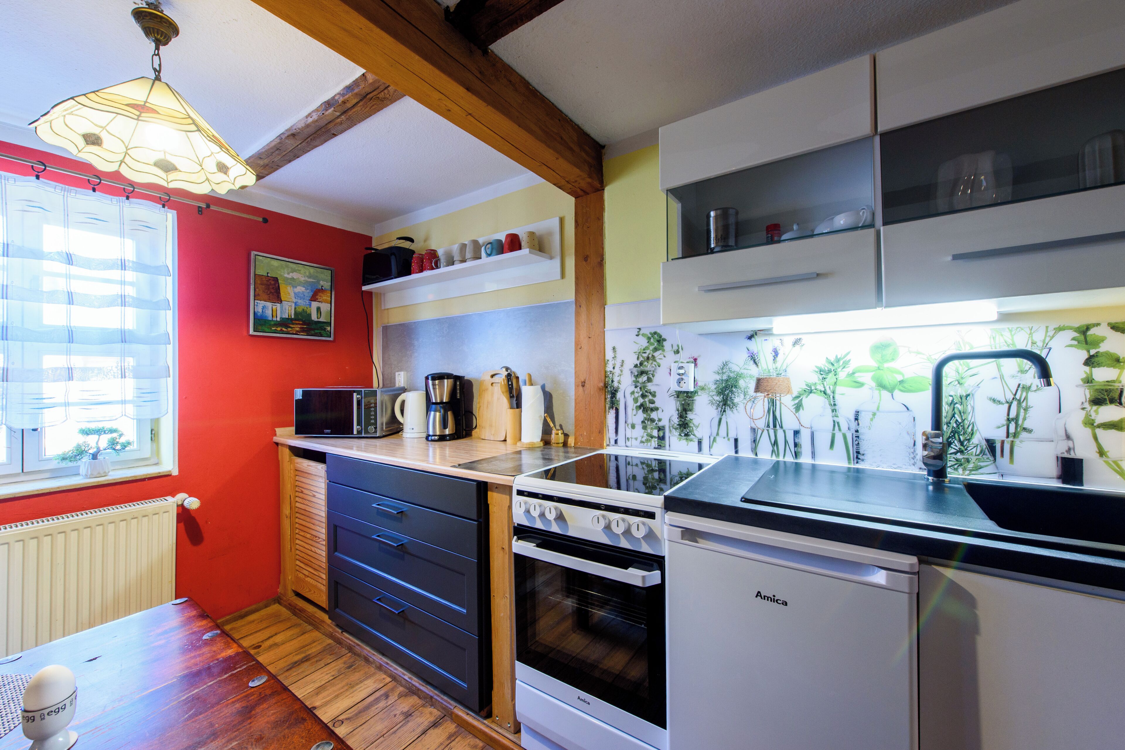 Una cocina con vigas de madera, estufa, microondas y un lavamanos.