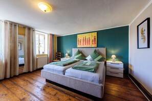 A double bed with a headboard, two bedside tables with lamps, a window with curtains, and a painting on the wall. - Vacation happiness - harmony and color (Quedlinburg)