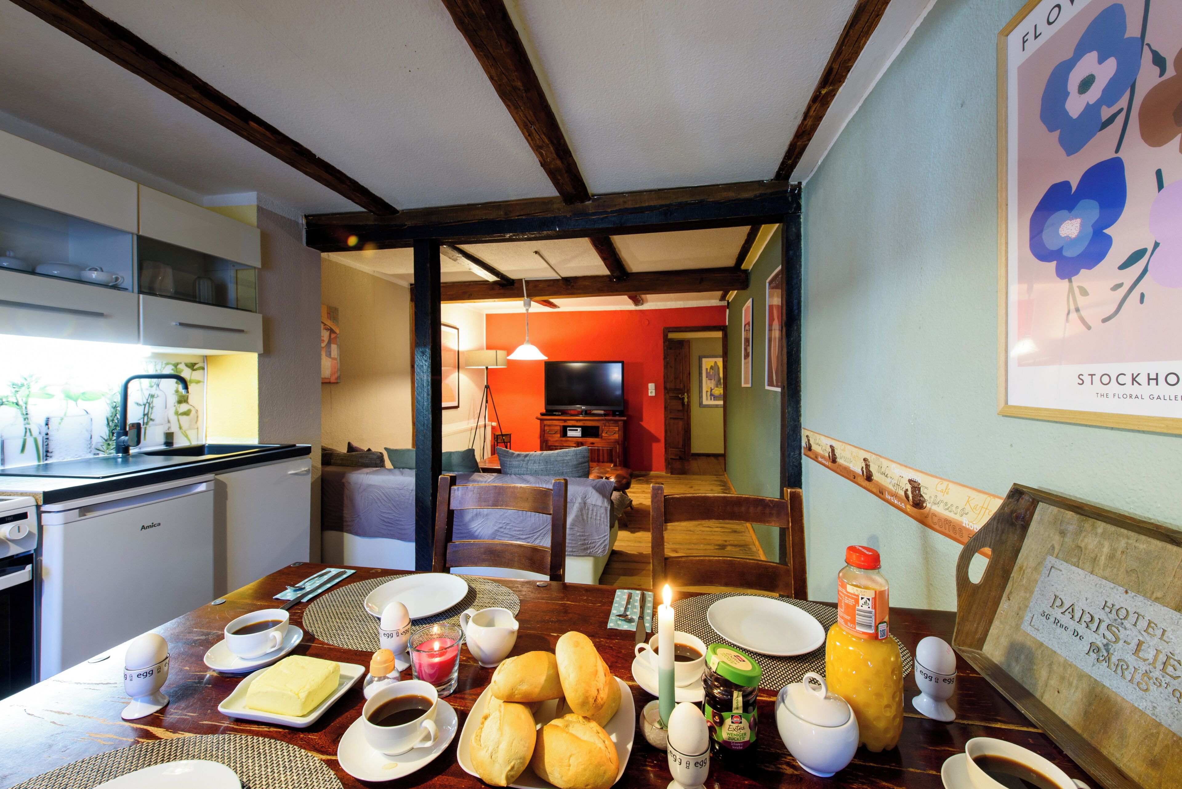 A dining table set with breakfast items, a candle, and a bottle of orange juice.