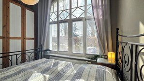 Une chambre à coucher avec un lit, une fenêtre avec des stores, un radiateur et une lampe sur une table de chevet.