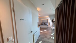 A modern bedroom with a bed, bedside tables, and a ceiling fan. - Anna Düne 3-41 - Dream location in the Aparthotel Anna Düne with a view of the Wadden Sea (Wangerooge)
