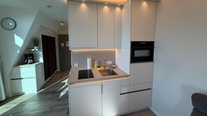 A modern kitchen with built-in appliances, a sink, and a clock on the wall. - Anna Düne 3-41 - Dream location in the Aparthotel Anna Düne with a view of the Wadden Sea (Wangerooge)