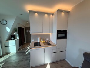 Eine moderne Küche mit integrierten Geräten, einer Spüle und einer Uhr an der Wand.