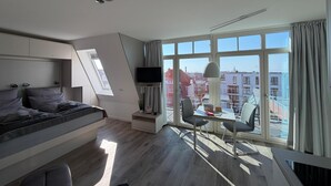 A modern bedroom with a bed, a desk, and a TV. - Anna Düne 3-41 - Dream location in the Aparthotel Anna Düne with a view of the Wadden Sea (Wangerooge)