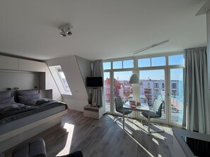 Ein modernes Schlafzimmer mit Bett, Schreibtisch und Fernseher.
