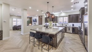 A spacious kitchen with a large island, dark cabinets, and modern pendant lighting. - 5000sf Renovated Luxury Villa near Summerlin (Las Vegas)