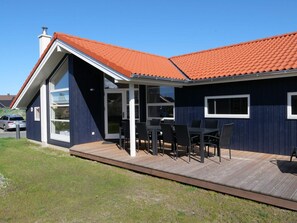 A modern house with a large glass door, a covered patio with outdoor furniture, and a red-tiled roof. - 4 Star Holiday Home in Grossenbrode (Grossenbrode)